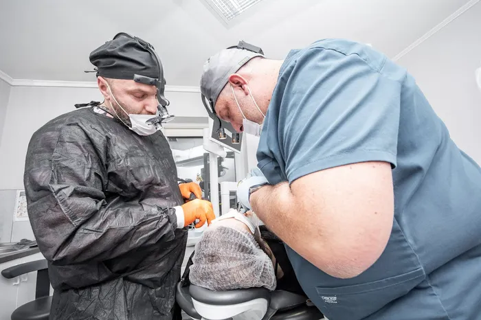 Two dental surgery professionals in sterile gowns and masks — the level of clinical expertise and infection control you should expect at an accredited dental clinic abroad